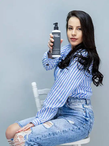 Жена с дълга коса, държащa маска F-Expert за боядисана коса на светъл фон.